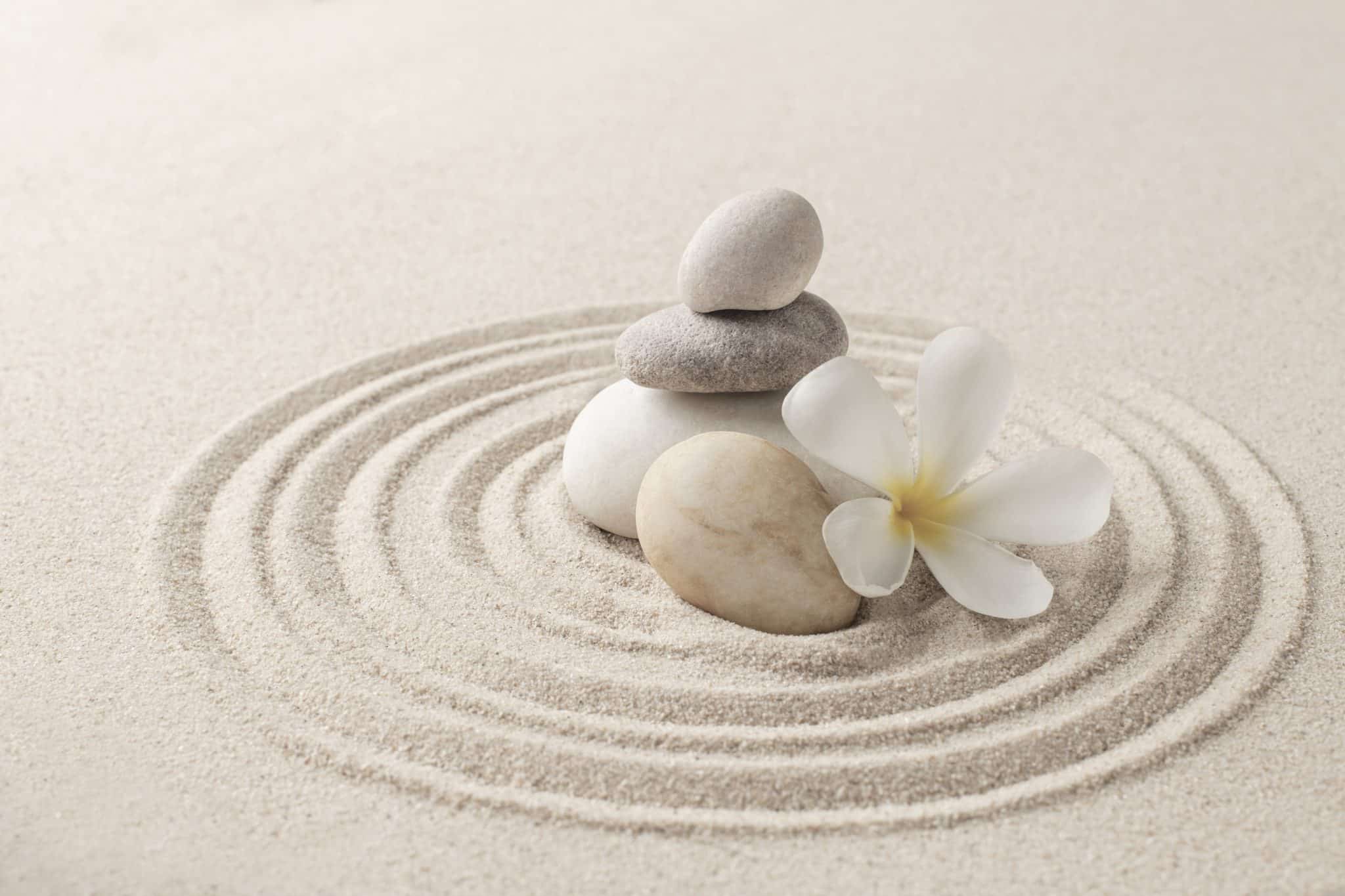Pierres zen en équilibre sur un sable japonais représentant l’harmonie et l’accompagnement bien-être.