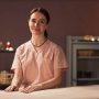 Happy cosmetologist standing at bed in spa salon